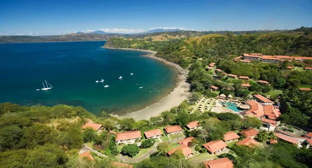 Aerial view of Secrets Papagayo Costa Rica nestled along a secluded bay surrounded by tropical forest.