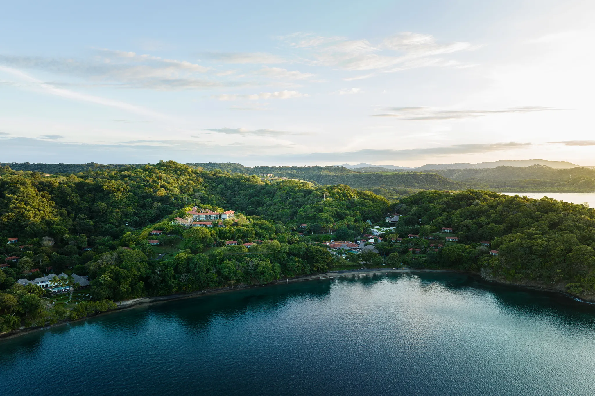 Aerial view of Secrets Papagayo Costa Rica nestled along the coastline with lush tropical hills.