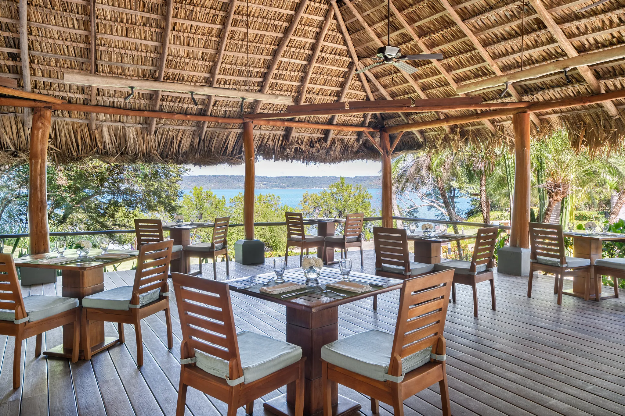 Aqua restaurant at Secrets Papagayo Costa Rica featuring an open-air dining terrace, wooden furnishings, thatched roof, and scenic ocean views.