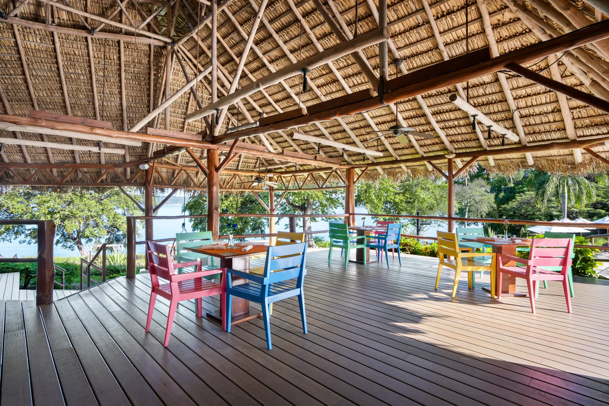 Barefoot Grill at Secrets Papagayo Costa Rica featuring an open-air poolside restaurant with colorful chairs, thatched roof, and tropical ocean views.