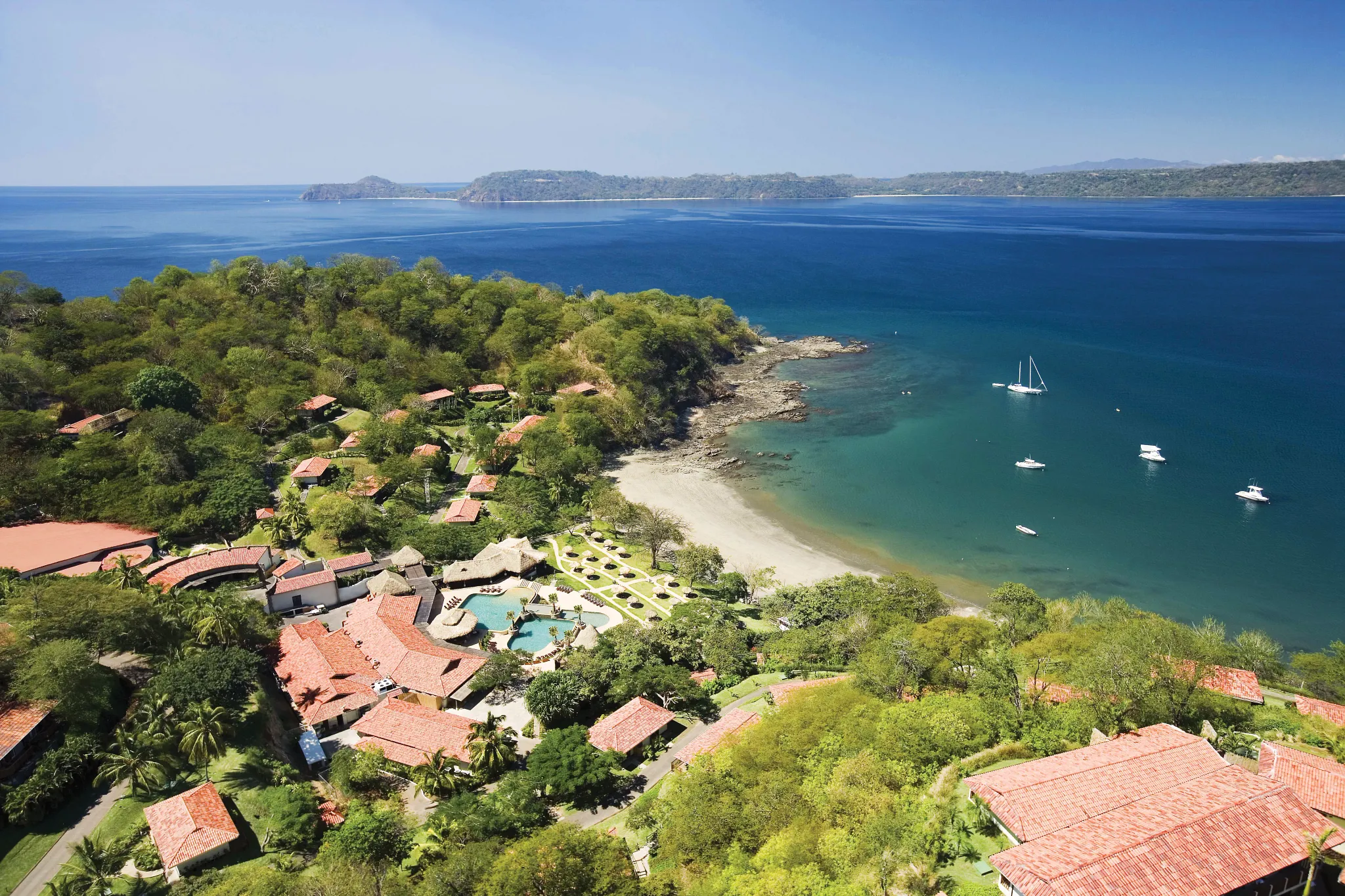 Aerial view of Secrets Papagayo Costa Rica coastline with tropical hills and Pacific Ocean waters.