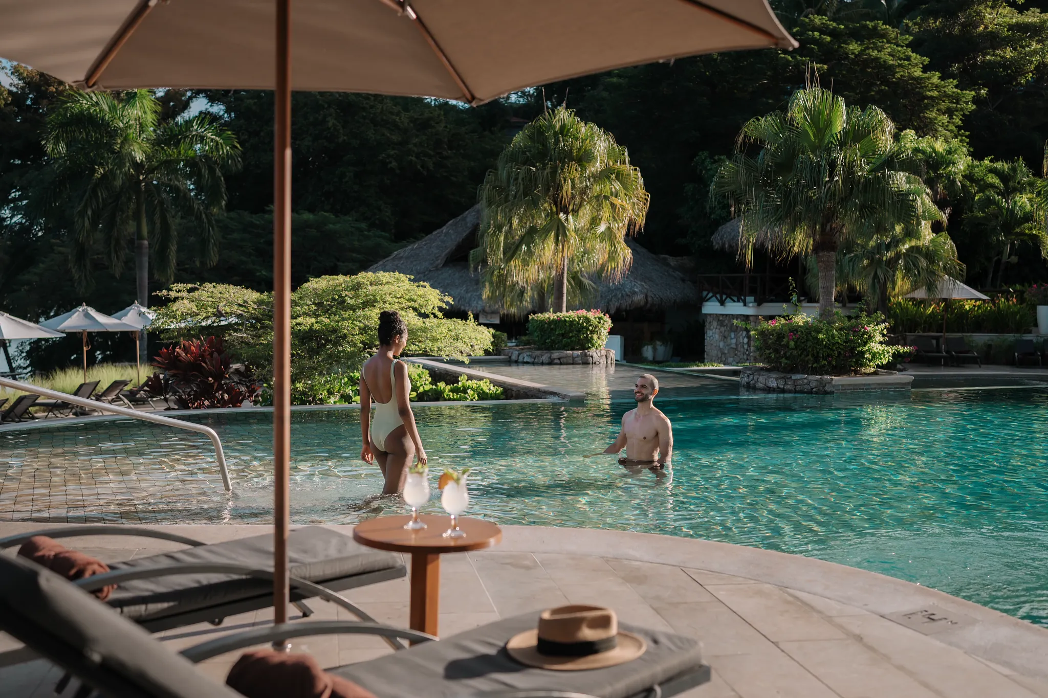 Couple relaxing together in the main pool at Secrets Papagayo Costa Rica, surrounded by tropical scenery.