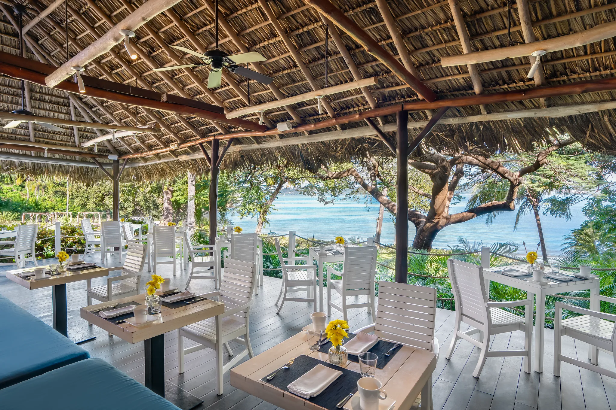 Seaside Grill at Secrets Papagayo Costa Rica featuring an open-air poolside restaurant with white tables, tropical greenery, and scenic ocean views.