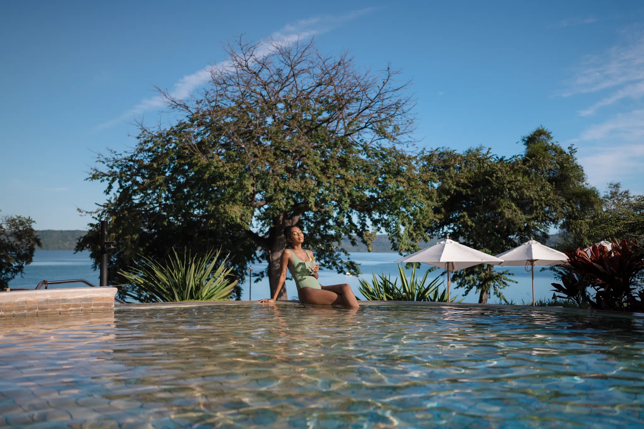 Woman relaxing in the pool overlooking the ocean at Secrets Papagayo Costa Rica, surrounded by lush tropical scenery.